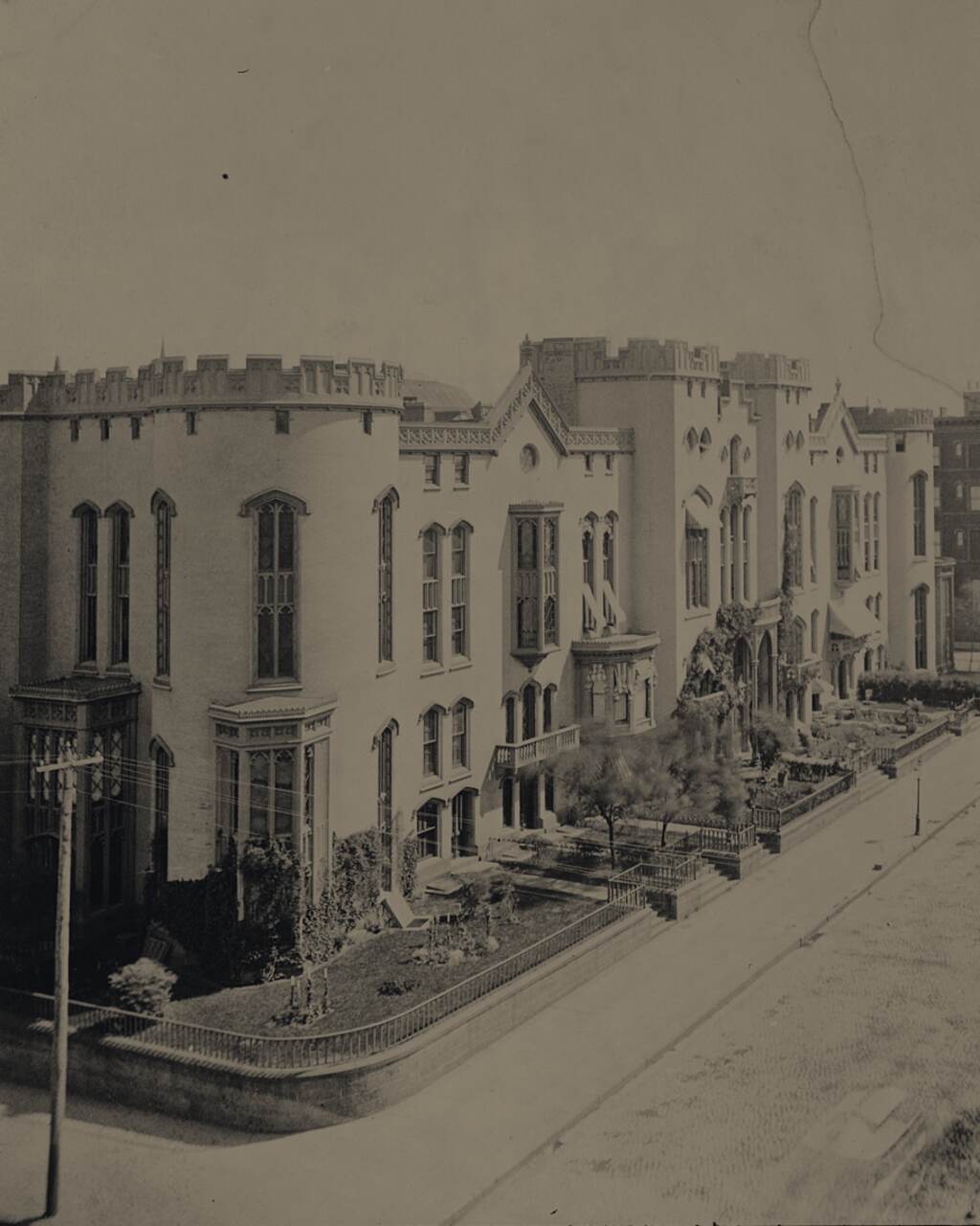Photograph looking down Fifth Avenue in 1880, castellated houses on the left, a church spire in the distance.