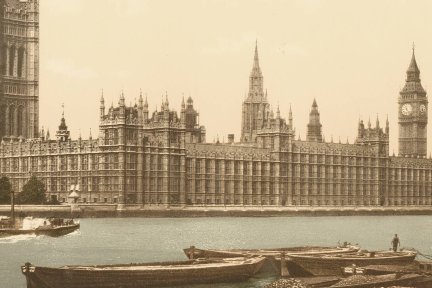 Photochrom of the Houses of Parliament from the river, barges working in the foreground.